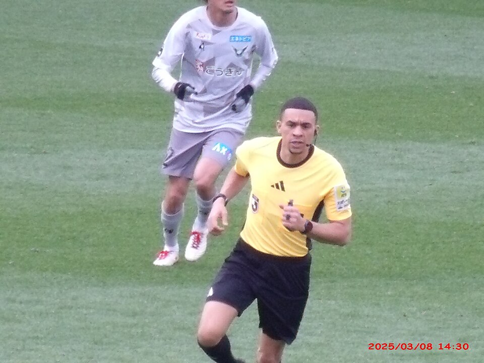 Delantero protegiendo la pelota ante dos defensores en un partido nocturno